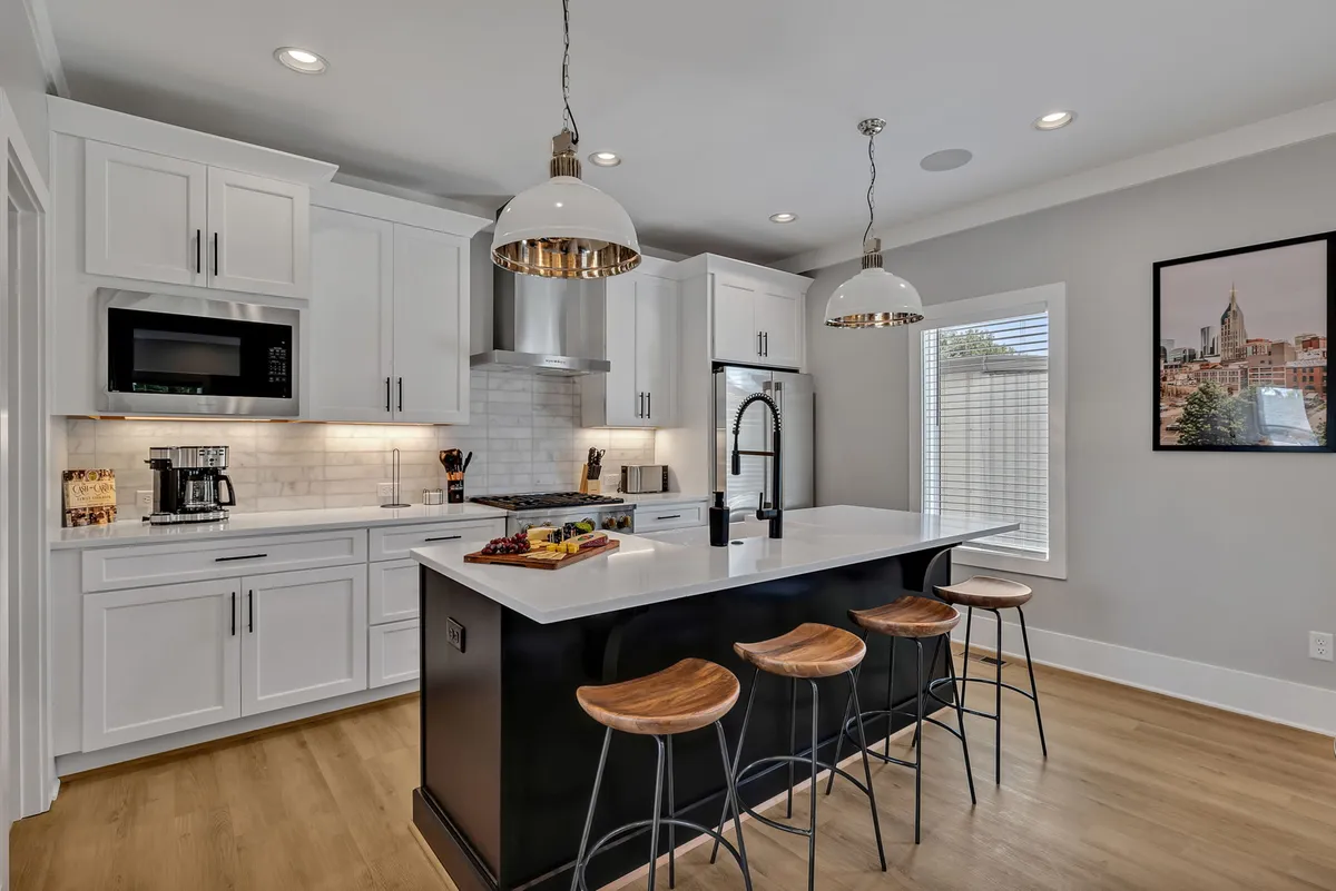 A modern kitchen featuring a spacious island countertop with bar stools, premium stainless-steel appliances, and vibrant wall art. The inviting setup is perfect for cooking, entertaining, and casual family dining, with plenty of space for culinary creativity and social interaction.