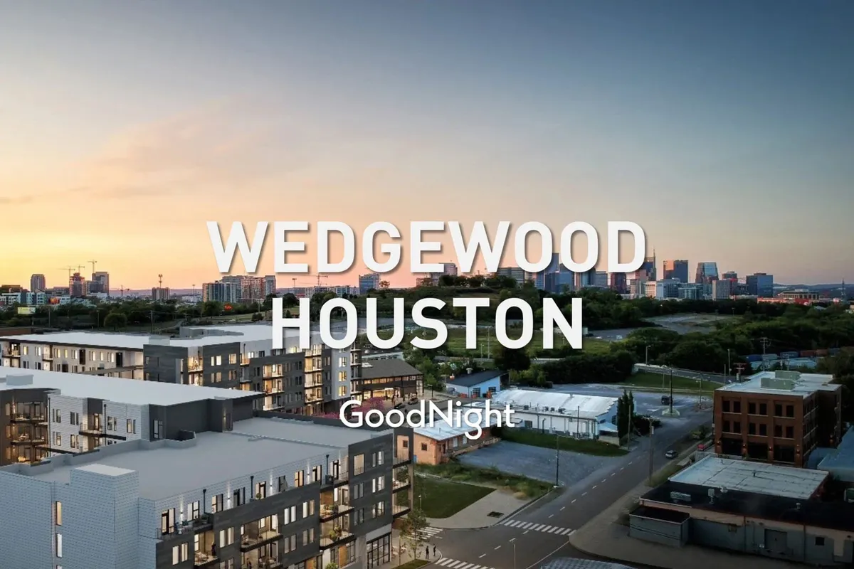 The image features modern apartment buildings set against the urban Nashville skyline, bathed in the warm glow of a sunset sky. The street below suggests walkability and easy access to city amenities, inviting exploration.