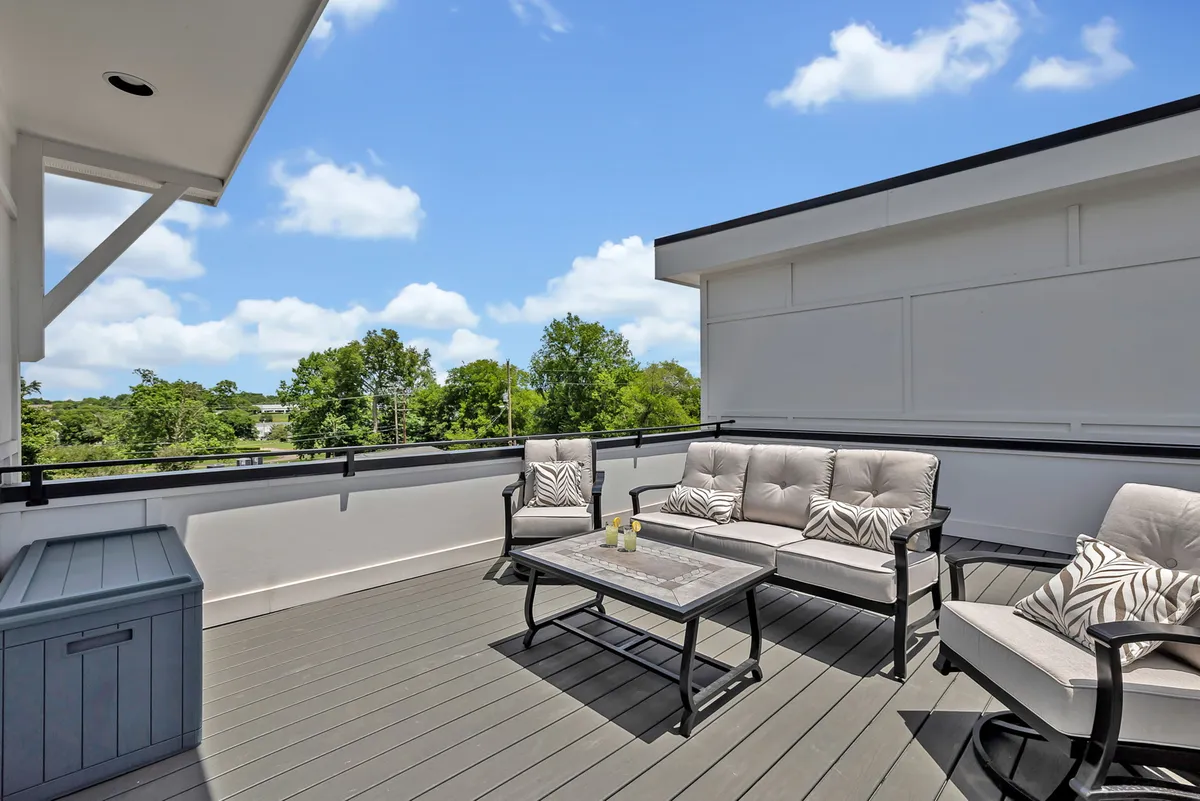 A stylish outdoor seating area on a rooftop, featuring a table with decorative items and plush chairs, surrounded by greenery. The ambiance is serene and inviting, ideal for both day and evening gatherings. The seating encourages guests to relax and take in the views, with space for group activities.